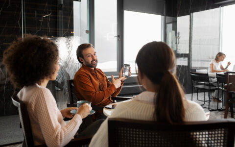Duas mulheres e um homem ao redor de uma mesa em um espaço coworking em Belo Horizonte