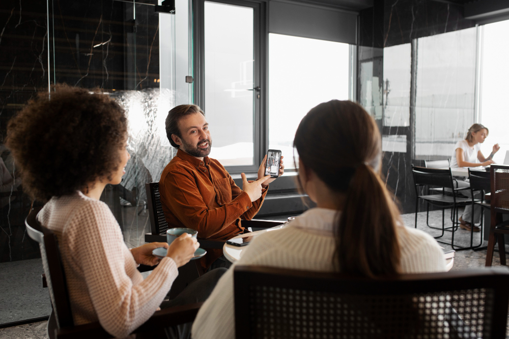 Duas mulheres e um homem ao redor de uma mesa em um espaço coworking em Belo Horizonte